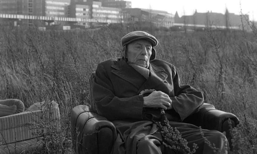 Een oude man in een fauteuil, op een braakliggend stuk Berlijn.